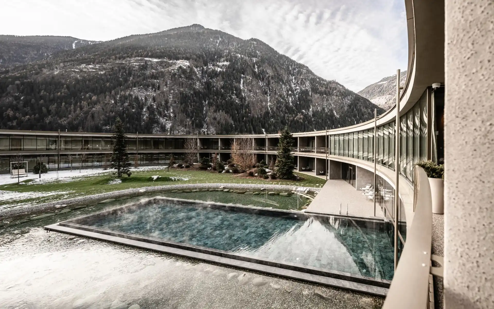 Hotel mit beheiztem Außenpool vor verschneiten Bergen